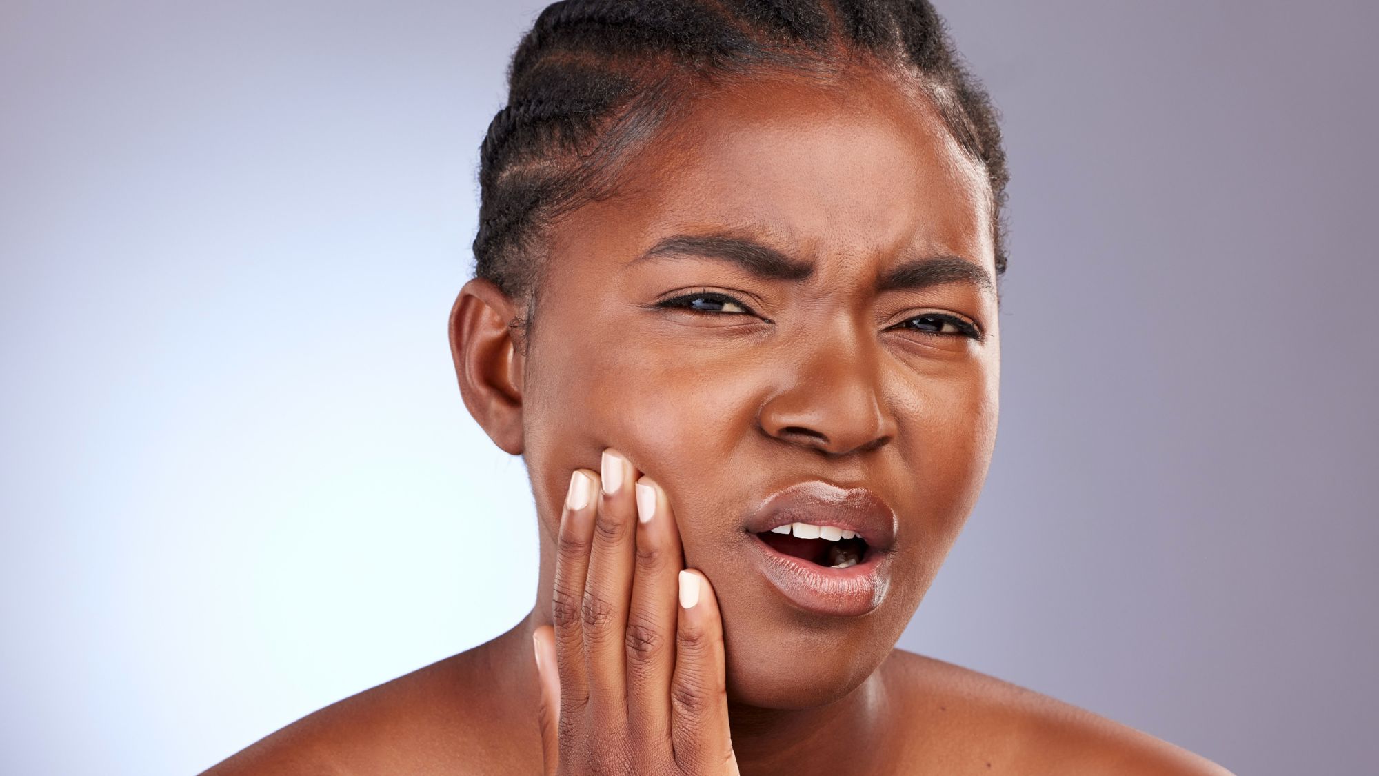 A young black woman holding her mouth, suffering from sensitive teeth pain